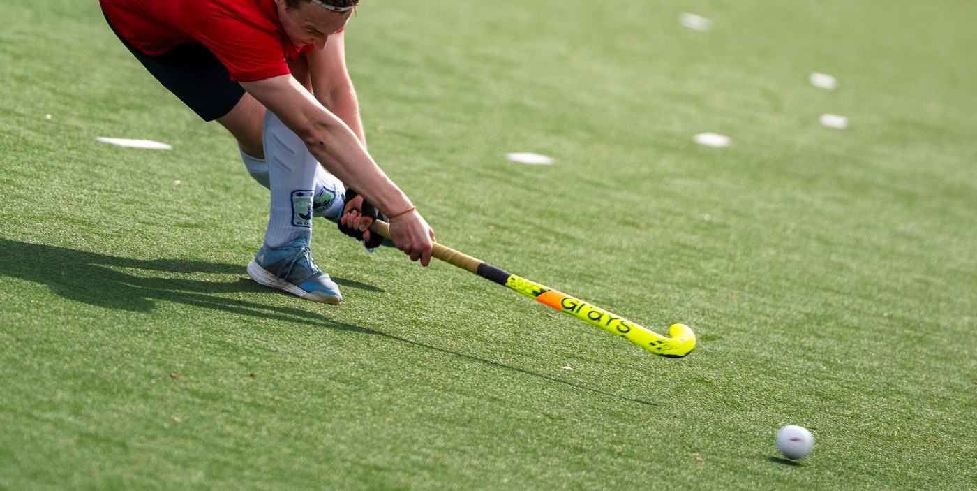Player hitting the ball with a Grays stick on artificial turf – the stick seen in profile