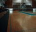 Pusta hala sportowa z drewnianym parkietem i drewnianymi barierkami przy trybunach